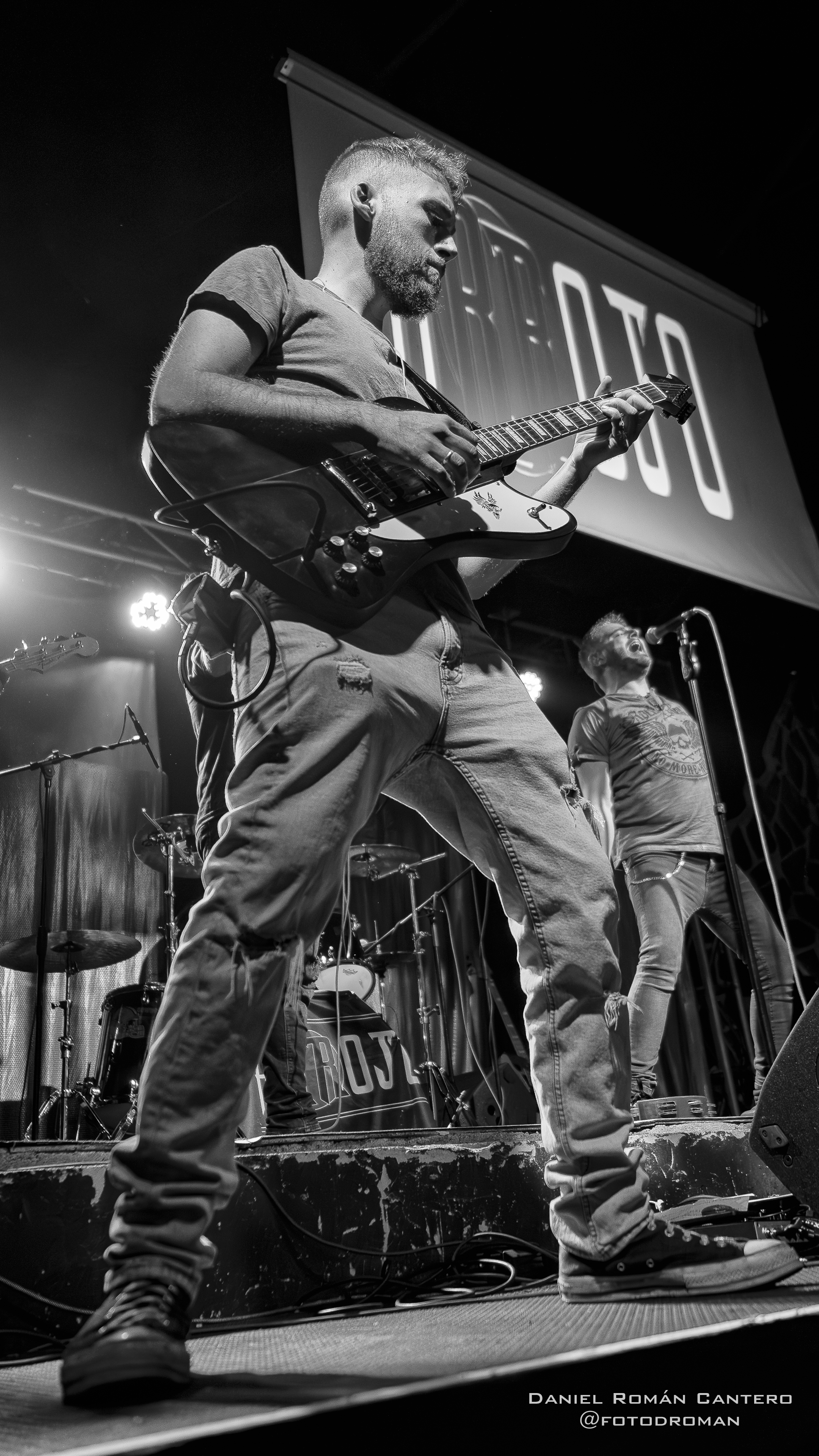 Guitarrista rítmico Guille tocando en directo bajo el logo de Arrojo