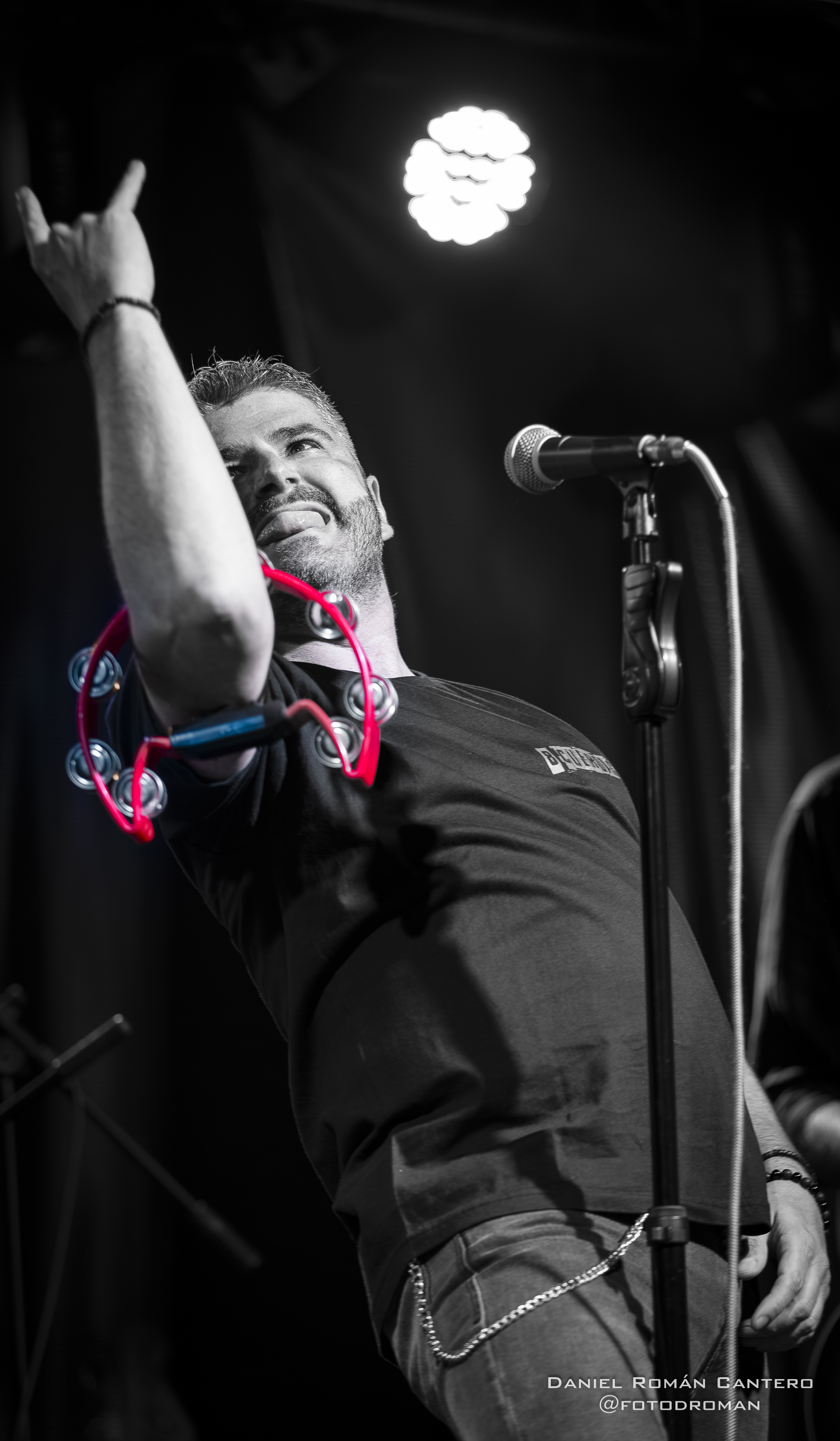 Cantante de Arrojo haciendo el gesto de los cuernos con una pandereta roja