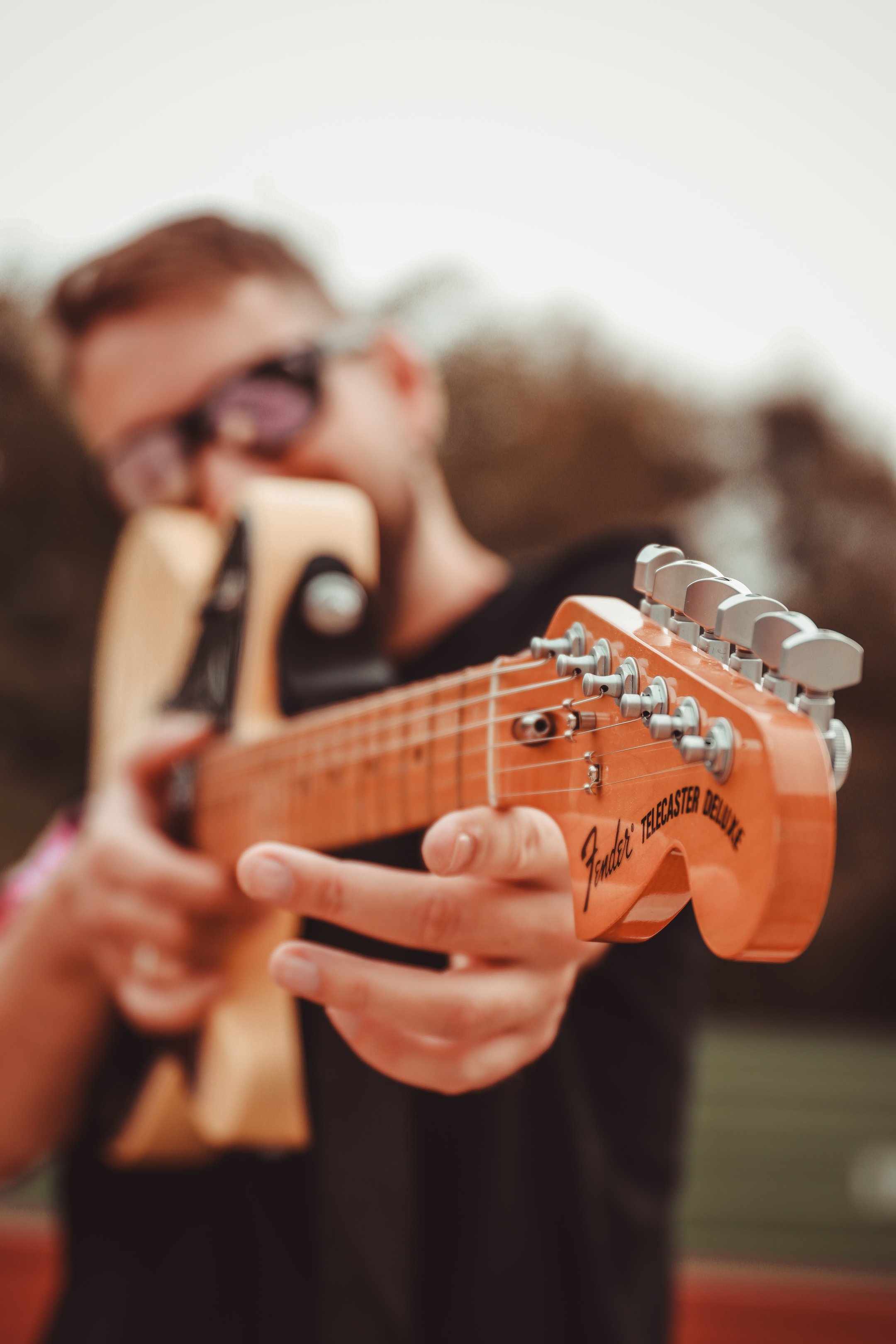Guitarrista apuntando el mástil de su guitarra Fender Telecaster Deluxe directamente a la cámara