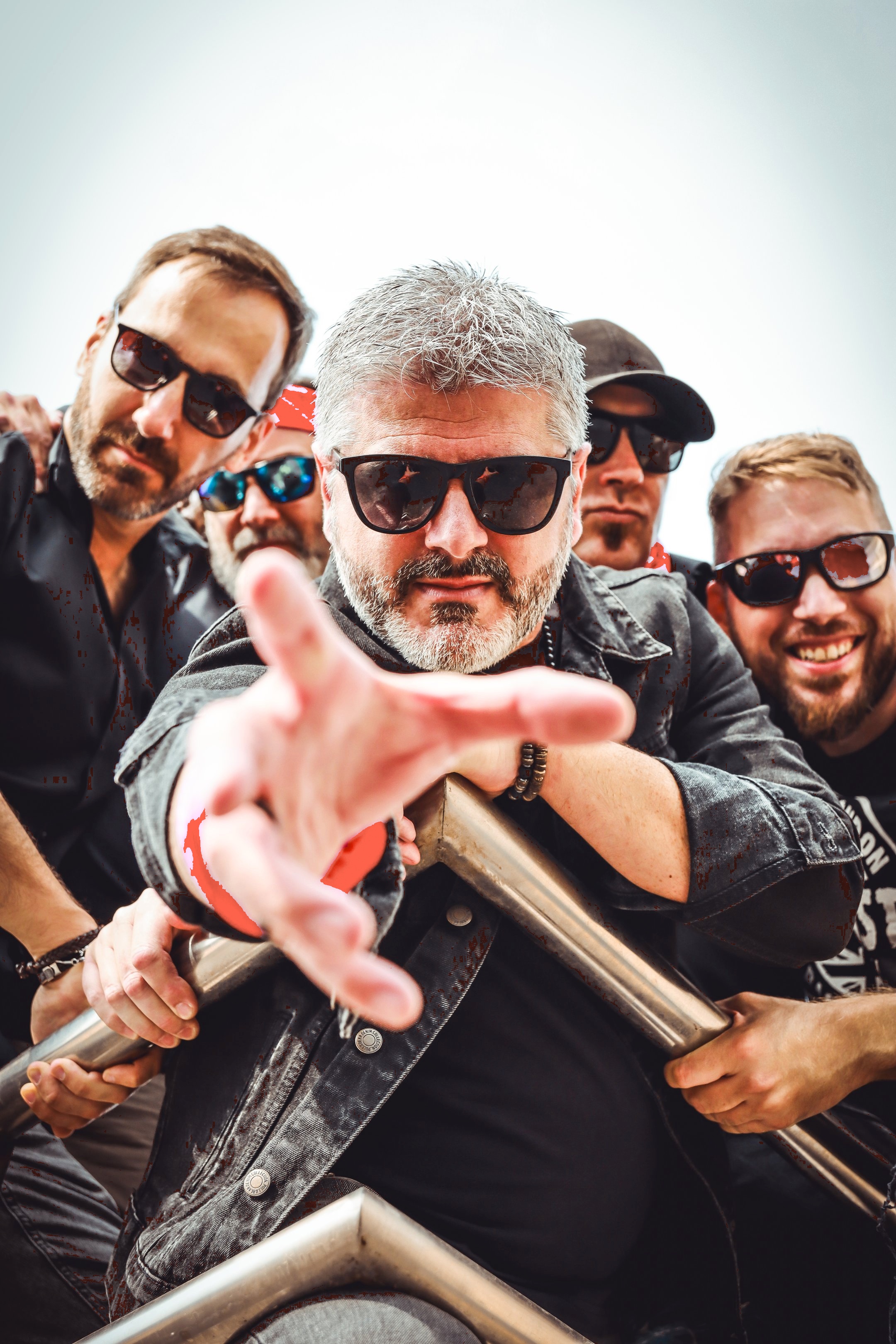 Retrato grupal de los cinco integrantes de la banda Arrojo posando juntos tras una barra metálica